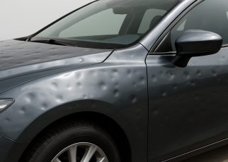 Close-up of a car hood with visible hail damage